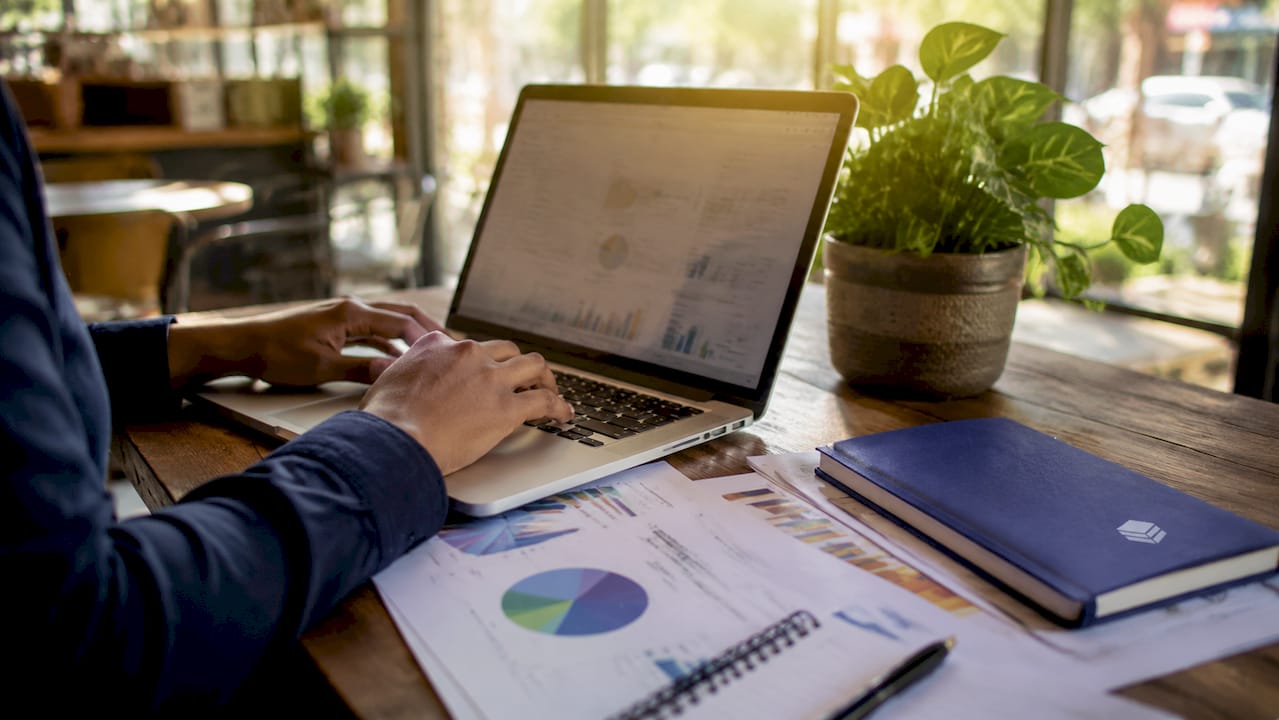 Hands typing on laptop with finance documents