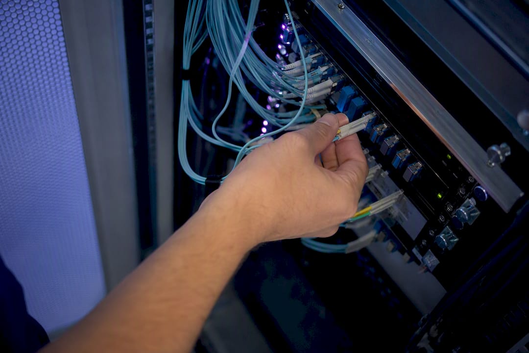 Hands plugging fiber optic cable in data center