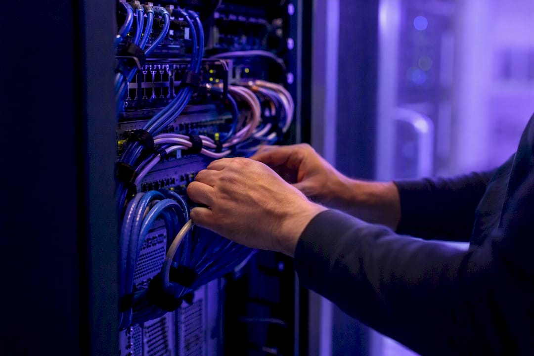 Hands adjusting cable in cloud data center rack