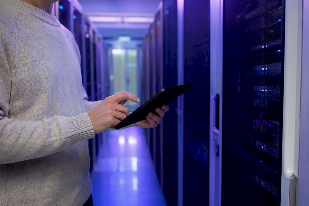 Engineer holding inactive tablet near servers